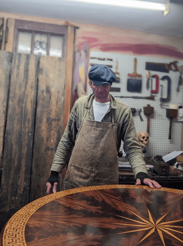 Rob Cain with beautifully restored table in The Old Polishing Shop